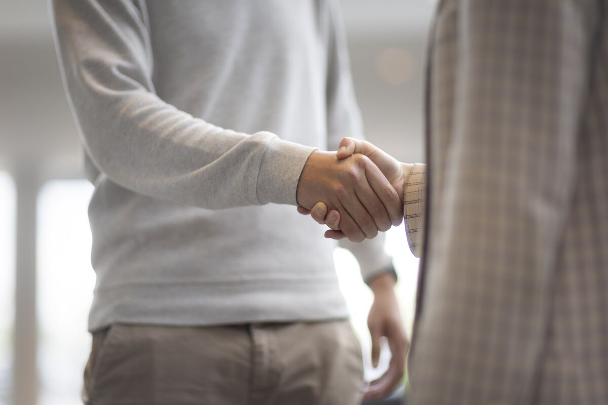 Bărbat și femeie își strâng mâna într-o clădire de birouri.