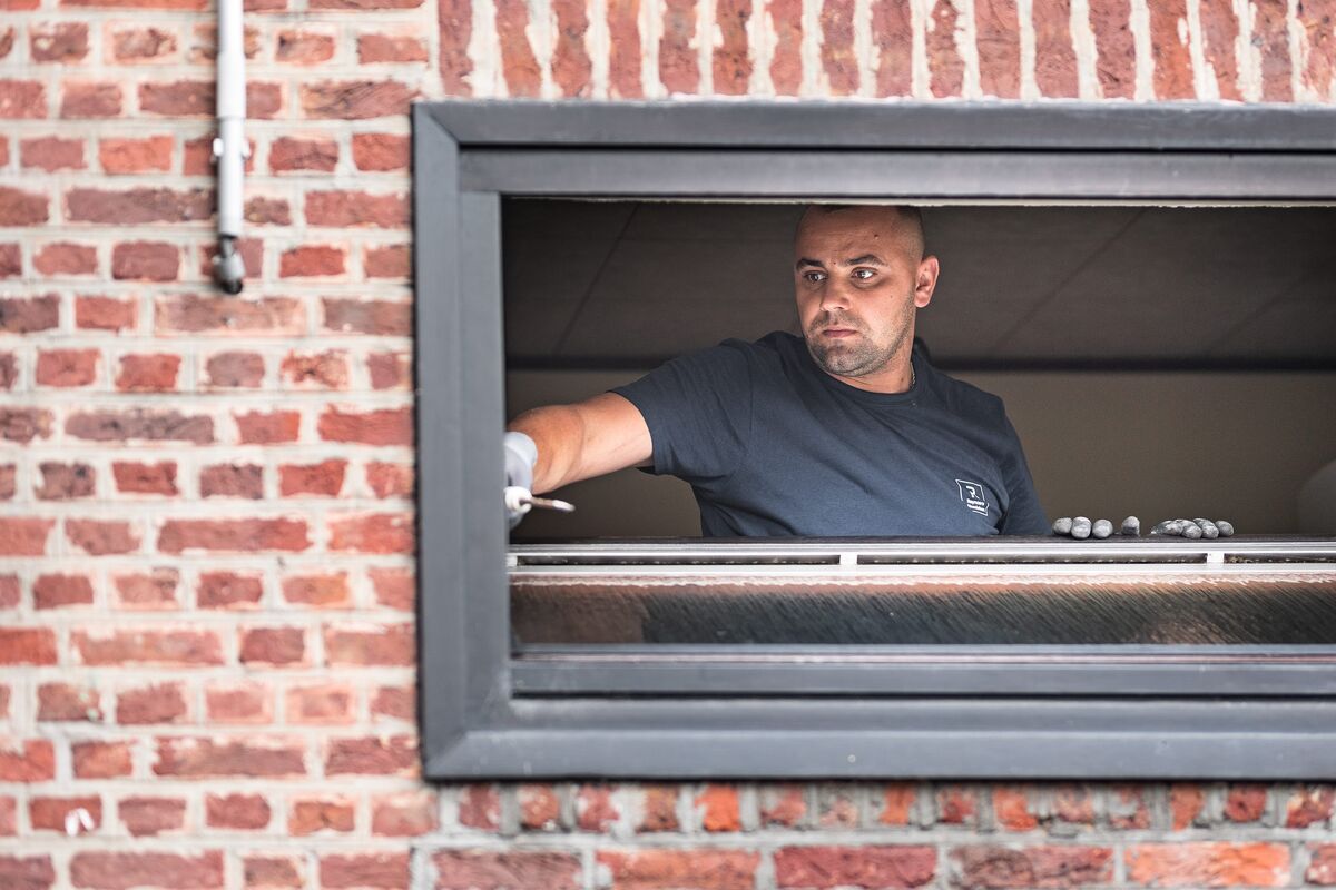 bărbat instalând rama ferestrei în peretele de cărămidă