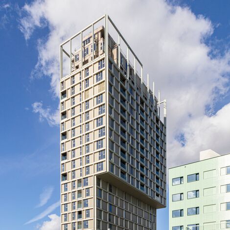 Clădire înaltă bej, cu multe ferestre, în centrul orașului.