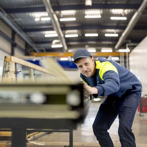 Fabricant aliniază profilele ferestrelor, purtând echipament de protecție.