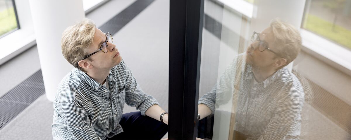 Bărbat cu ochelari ține un profil negru de aluminiu.