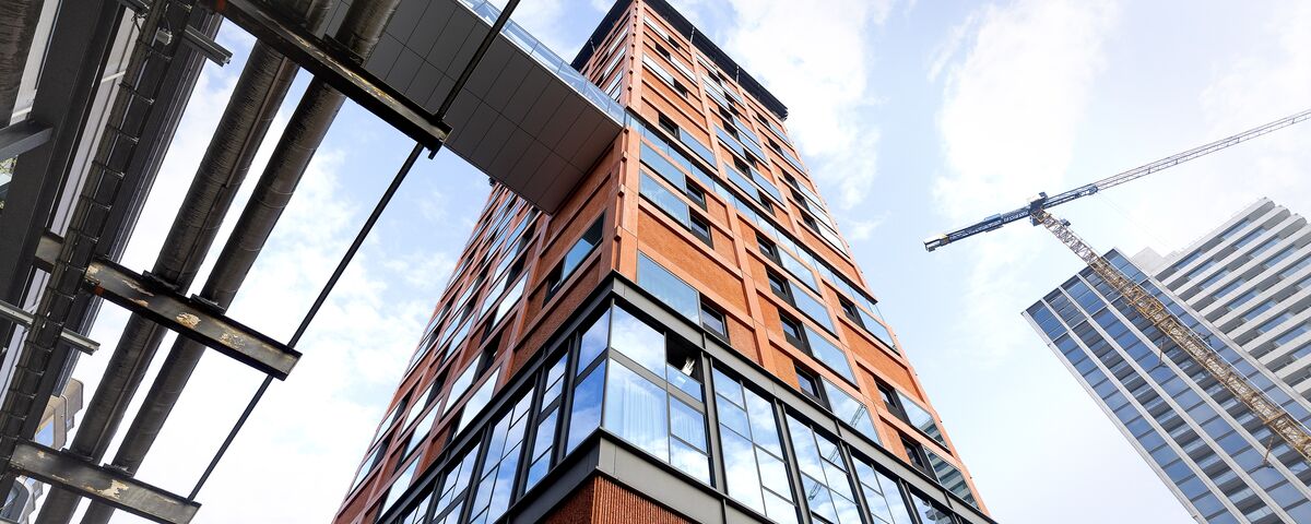 Clădire înaltă, de culoare portocalie, privită de la nivelul solului. 