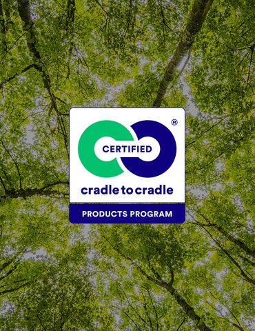 Sigla Cradle to Cradle în fața vârfurilor verzi ale copacilor.