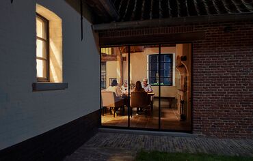 Outside view of family sitting at dinner table at night.