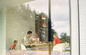 Gezin zit aan tafel en kijkt naar buiten door aluminium raam