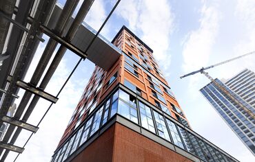 Clădire înaltă, de culoare portocalie, privită de la nivelul solului. 