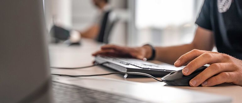 Reynaers Aluminium employee using a mouse and keyboard at his desk.